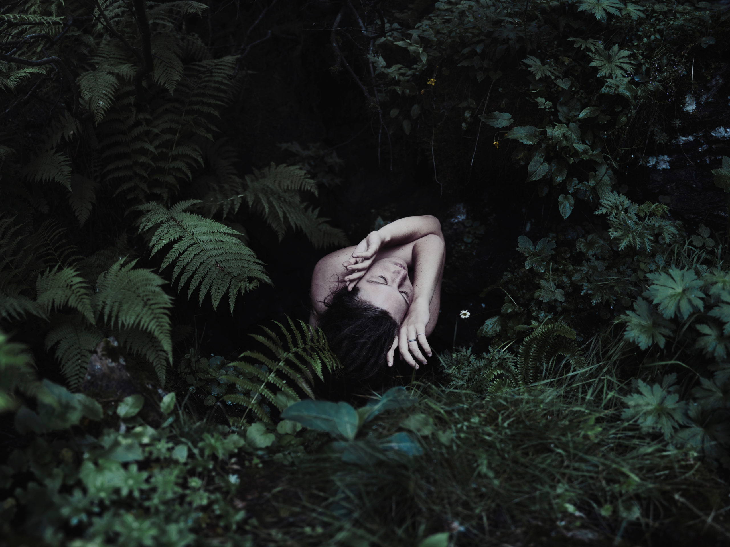 Sensual self portrait photograph showing a woman surrounded by forest plants.