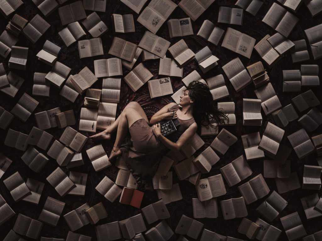 Self portrait photography by Anna Heimkreiter. The creative artwork shows a girl from above surrounded by books.