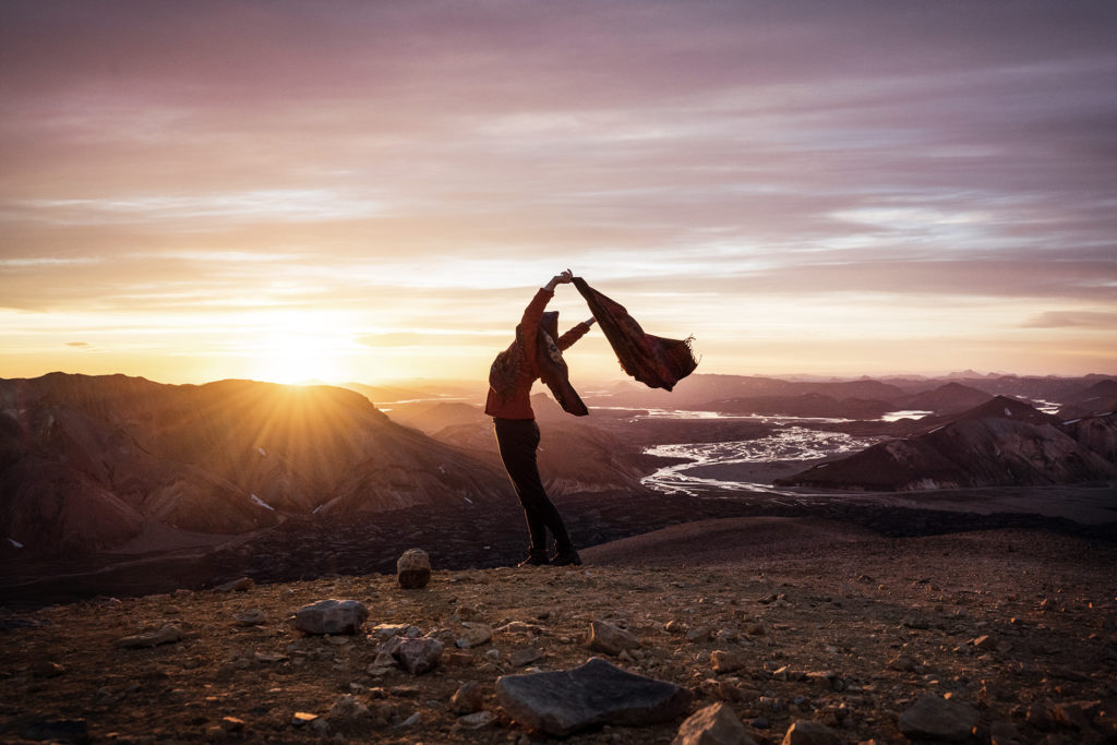A hiker enjoying the feeling of freedom on top of a mountain at sunrise