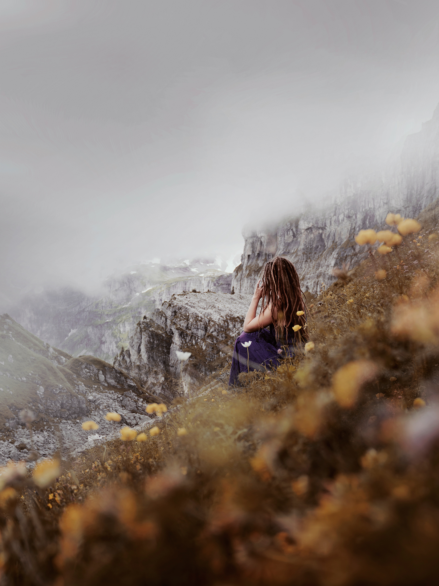 A woman sitting in an alpine mountain meadow full of wild flowers.
