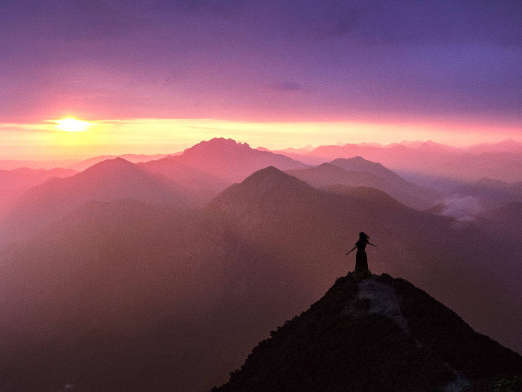 Layers of mountains at sunrise with a small person enjoying the freedom.