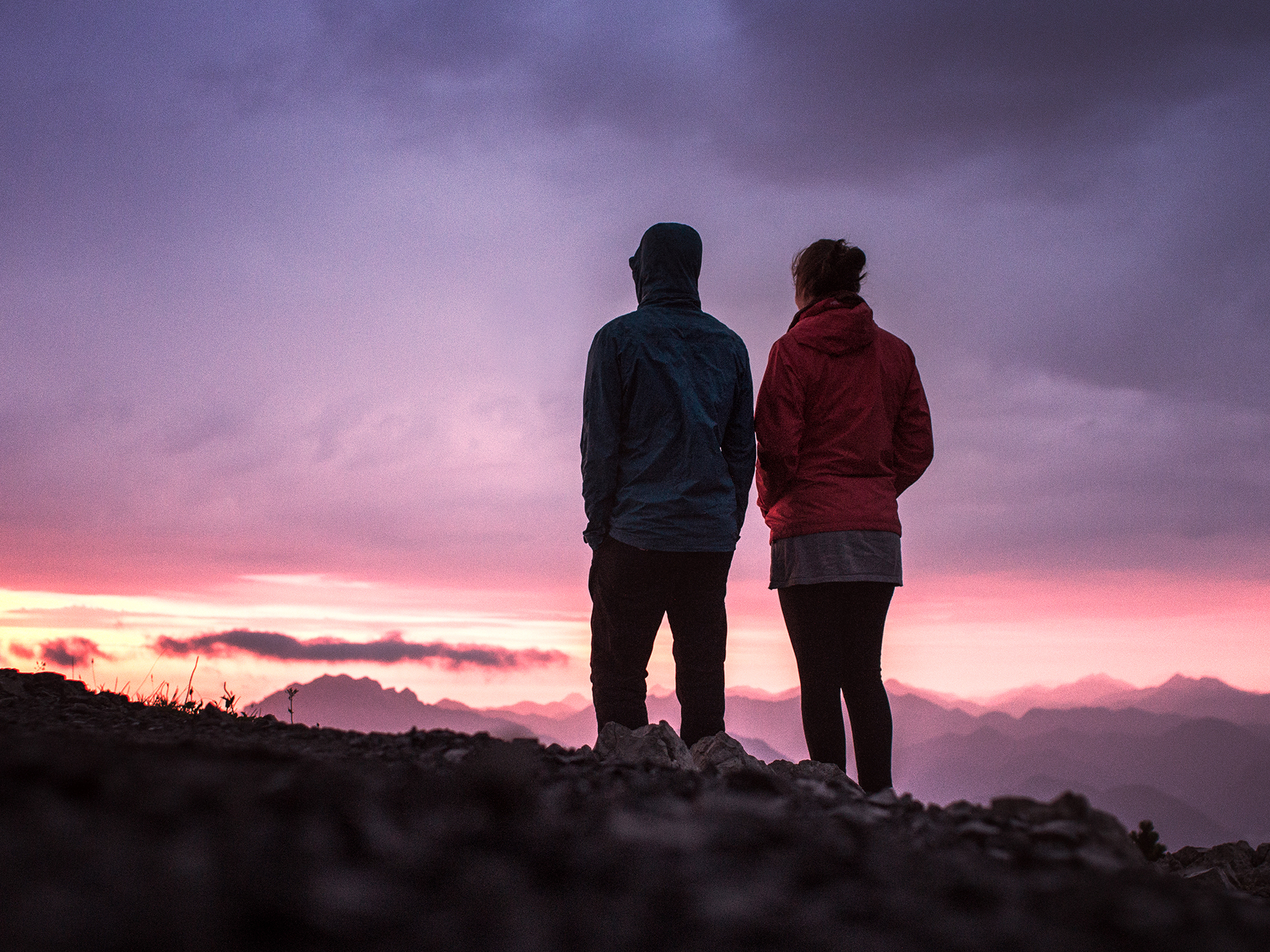 Two hikers watching an early morning mountain sunrise.