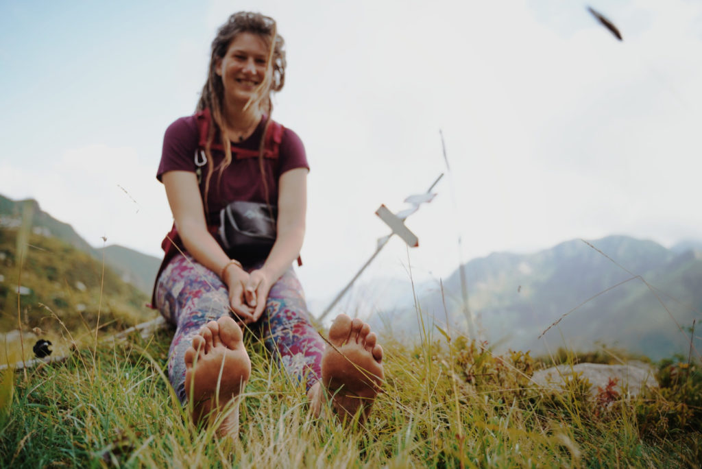 A barefoot hiker sitting in the grass.