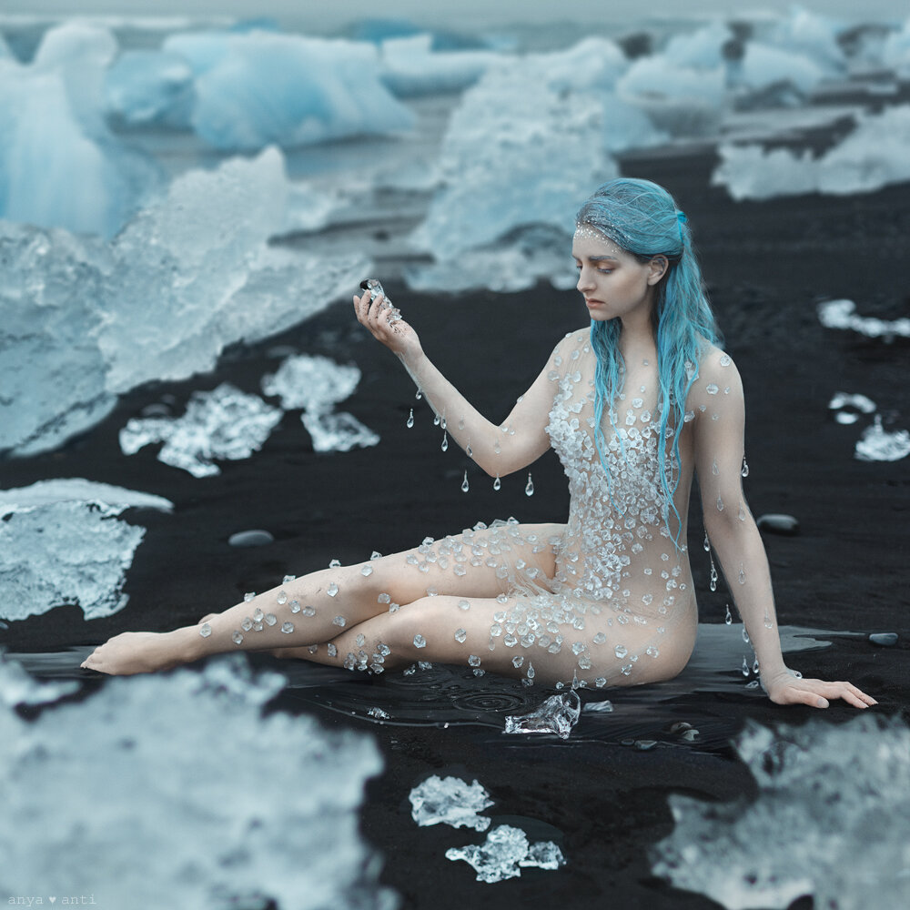 Photographer Anya Anti on a dark beach surrounded by glacier pieces.