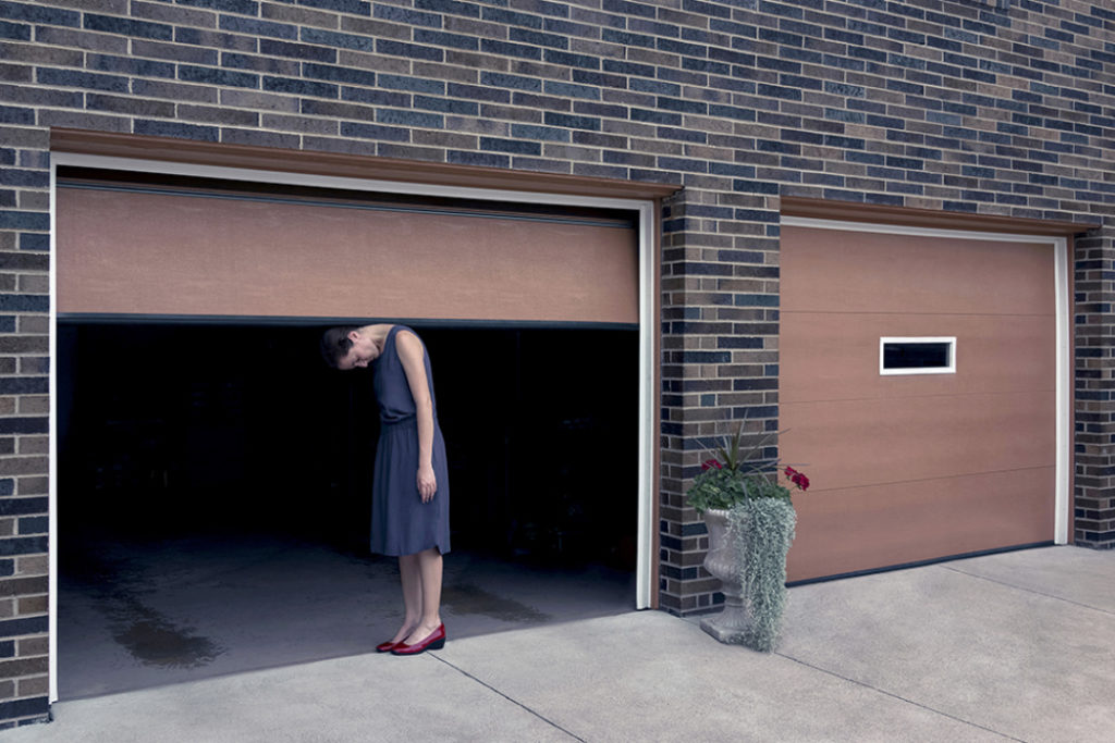 A creative self portrait of a woman standing in a garage architecture surrounding.
