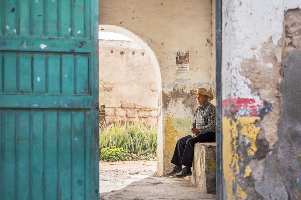 A man sitting in the shade in a remote village in Mexico.