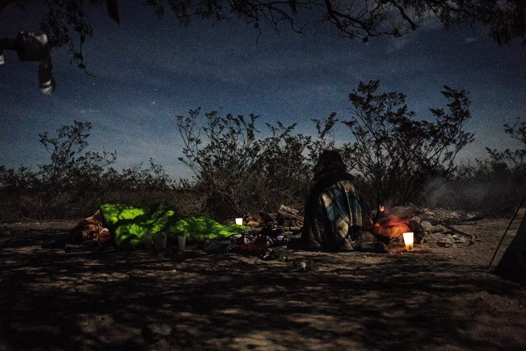 Two people sitting by the fire holding a Peyote ceremony in Mexico, far out in the desert.