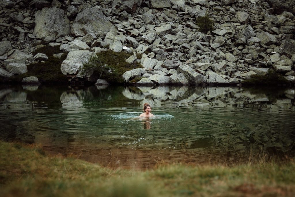 A woman happily swimming in an ice-cold mountain lake in the alps.