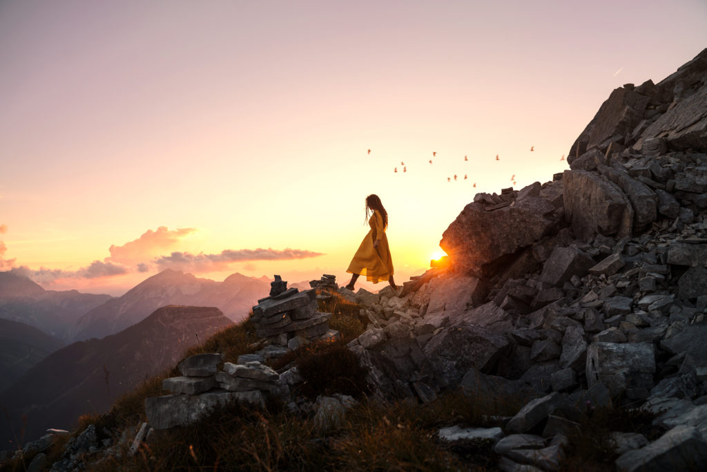 Self portrait photography by Anna Heimkreiter. The photo shows a woman wandering through the mountains at sunset. The mood is calm and peaceful.