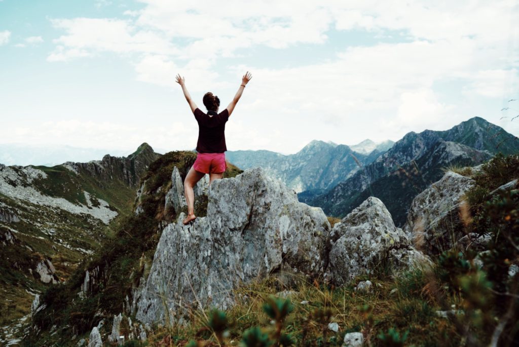 A hiker in a celebratory pose in the alps.