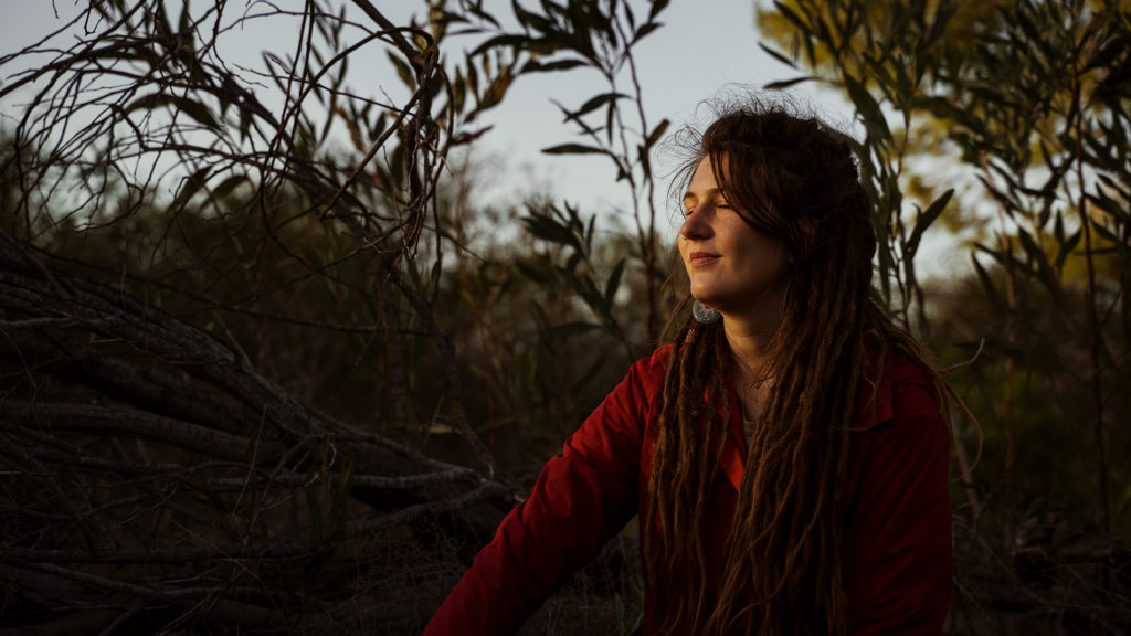 A female slow traveler enjoying the last sunrays on her face.