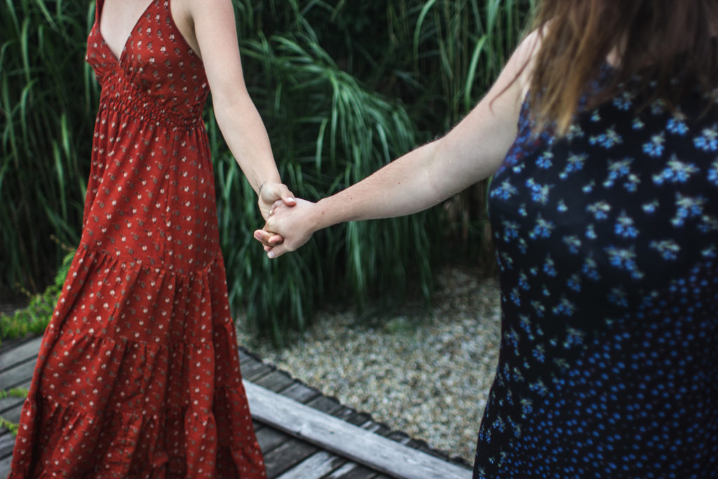 Two female friends holding each other's hand. Reducing social media can help to connect in real life.