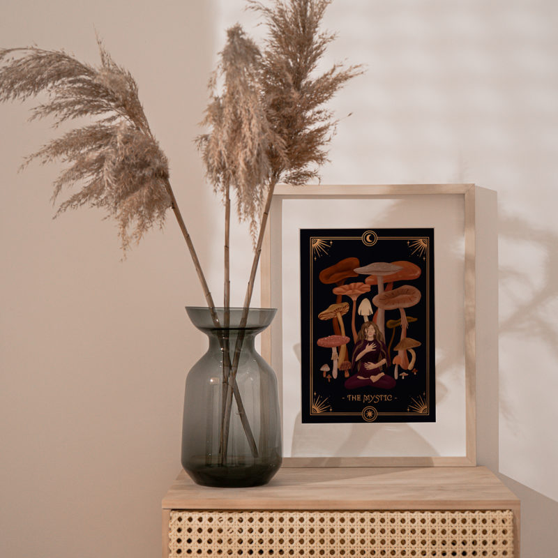 A boho interior with a dried plant in a vase showcasing a fine art print. The artwork shows an illustration of the Mystic Archetype, one of the 7 Feminine Archetypes, with a calm and peaceful aura.