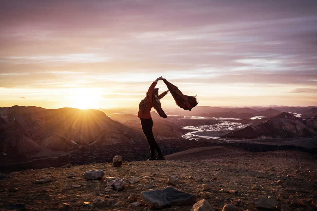 This Iceland photograph captures an incredible sunrise in Landmannalaugar. It shows a person letting their scarf blow in the wind, evoking a strong sense of freedom.