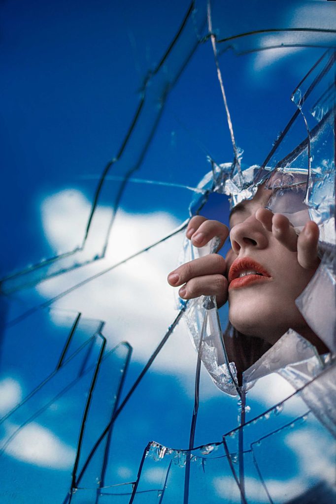Mirror self-portrait photography by Amelie Satzger. A face looks through a broken mirror.